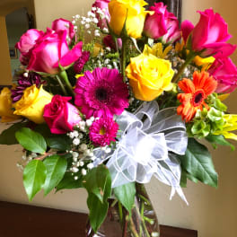Bouquet of pink and yellow roses with gerbera daisies in a glass vase
