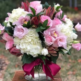 Pink and white bouquet in a glass vase with a magenta ribbon