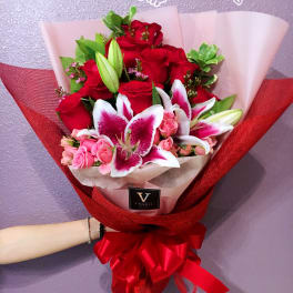 Bouquet of red roses and pink lilies wrapped in red and white paper