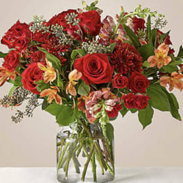 Red roses and mixed blooms arranged in a clear glass vase