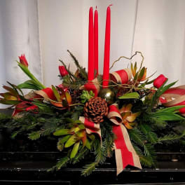 Holiday centerpiece with red candles, pinecones, and red ribbon