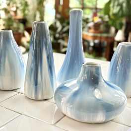 Five light blue ceramic vases on a tiled surface