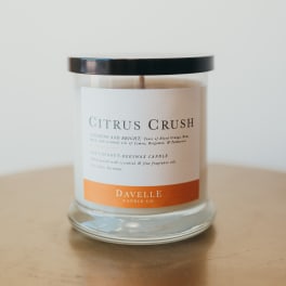 A citrus-scented candle in a clear glass jar with a black lid
