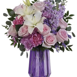 Pink roses and white lilies in a purple glass vase