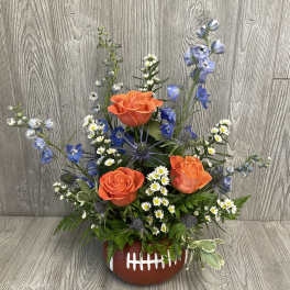 Football-shaped floral arrangement with orange roses and blue flowers