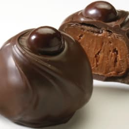 Two chocolate truffles on a white surface