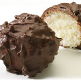 Two chocolate-covered coconut candies on a white surface