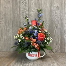 Mixed flower arrangement in a white mug with red lettering