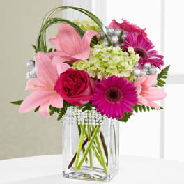 Pink lilies and magenta gerbera daisies in a clear glass vase