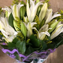 Bouquet of white lilies with yellow filler flowers and purple wrap
