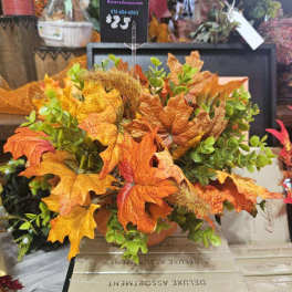 Autumn arrangement with orange maple leaves and green foliage in a container.
