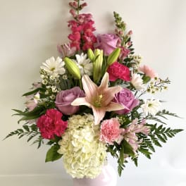 Pink and white mixed flower arrangement in a pale vase