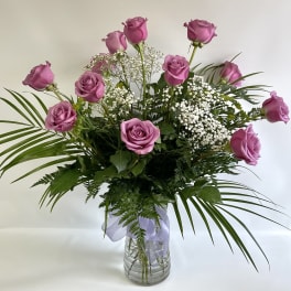 Pink roses arranged in a clear glass vase with baby's breath