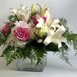 Pink roses and white lilies in a clear glass vase