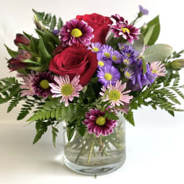 Bouquet of red roses and purple daisies in a glass vase