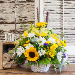 Basket arrangement with sunflowers, white daisies, and yellow roses
