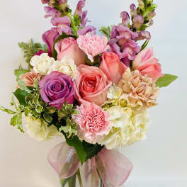 Pink and purple bouquet in a glass vase with a pink ribbon