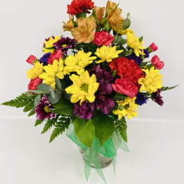 Colorful mixed bouquet in a clear glass vase with a green ribbon
