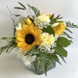 Sunflower and yellow rose bouquet in a square glass vase