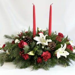 Holiday centerpiece with red candles, white lilies, and pinecones