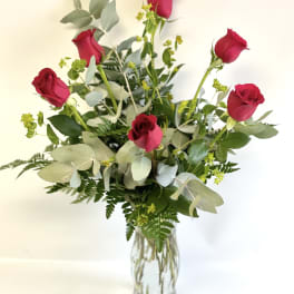 Red roses in a clear glass vase with mixed greenery