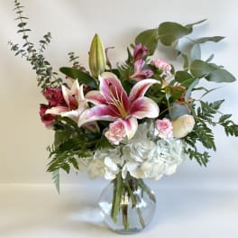 Pink lilies and white hydrangeas in a clear glass vase
