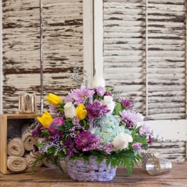 Basket arrangement of purple, yellow, white, and blue flowers