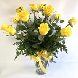 Yellow roses in a clear glass vase with a yellow ribbon