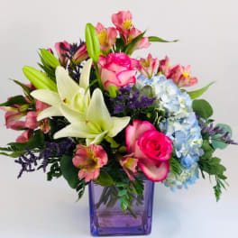 Mixed bouquet with lilies, roses, hydrangea, and alstroemeria in a purple vase