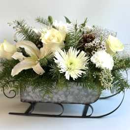 Winter floral arrangement in a sleigh-shaped container with white blooms