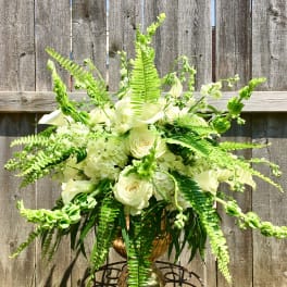 Large white rose and hydrangea arrangement with ferns in a gold urn on a metal stand