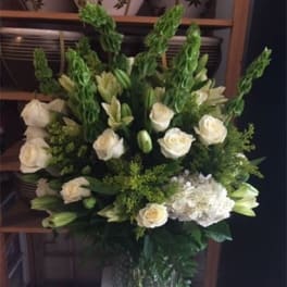 White roses and lilies in a tall vase arrangement