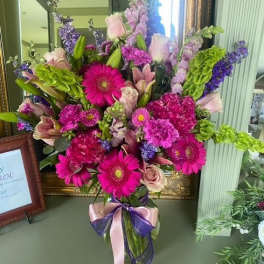 Bright mixed bouquet with pink gerberas, roses, and purple blooms in a vase