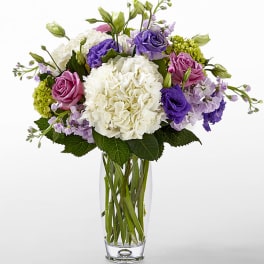 Bouquet of white hydrangea, purple and pink roses in a clear glass vase