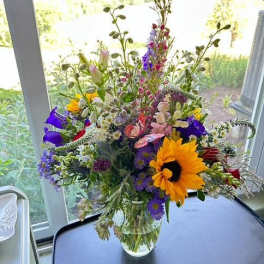 Mixed bouquet in a clear glass vase with a large yellow sunflower