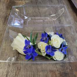 White roses and blue flowers in a clear plastic box