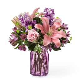 Pink lilies and roses in a purple glass vase
