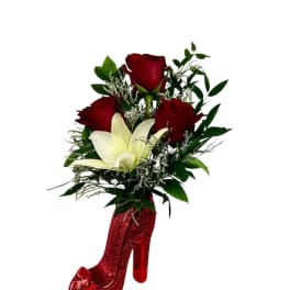 Red roses and a white lily arranged in a glittery red high-heel vase