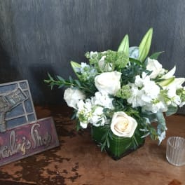 White roses and lilies arranged in a green vase.
