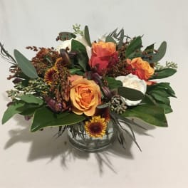 Low arrangement of orange and white roses with yellow mums in a clear glass vase