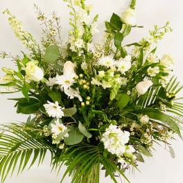 Tall white floral arrangement in a clear glass vase