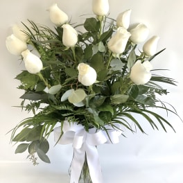 White roses in a glass vase with a white ribbon