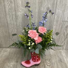 Pink carnations and blue delphinium in a pink cowboy boot vase