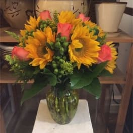 Bouquet of sunflowers and pink roses in a glass vase