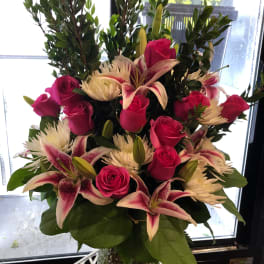 Pink roses and lilies arranged in a clear glass vase