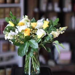 Yellow and white flower bouquet in a clear glass vase