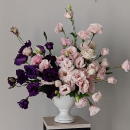 Pink and purple flowers arranged in a white vase