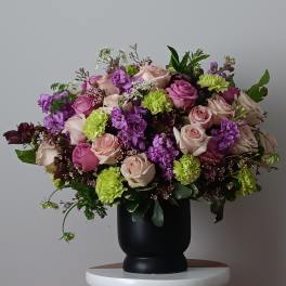 Large bouquet of pink and purple roses in a black vase