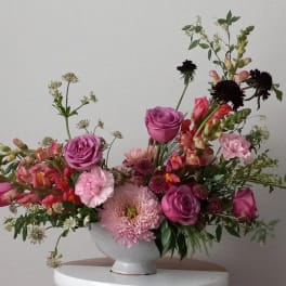 Pink and purple mixed flower arrangement in a white vase