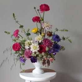 Mixed bouquet of colorful flowers in a white pedestal vase